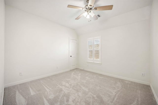 carpeted spare room with visible vents, ceiling fan, baseboards, and vaulted ceiling