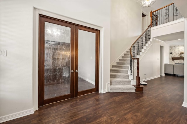 entryway featuring stairway, wood finished floors, baseboards, french doors, and a towering ceiling