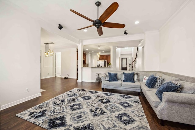 living area featuring dark wood-style floors, ceiling fan with notable chandelier, crown molding, and baseboards