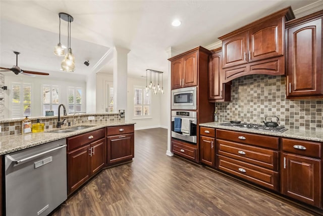 kitchen with decorative light fixtures, light stone counters, appliances with stainless steel finishes, and a sink