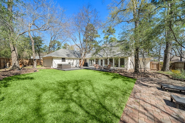 back of property with a patio, a fenced backyard, a lawn, and a hot tub