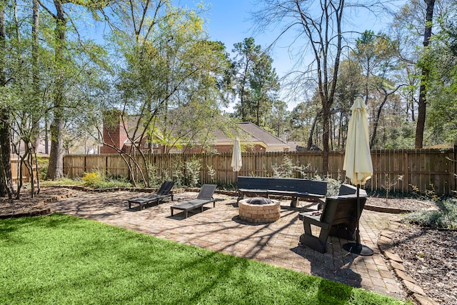 view of yard with a fenced backyard, a fire pit, and a patio