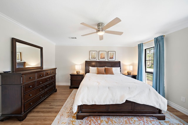 bedroom featuring wood finished floors, visible vents, baseboards, ceiling fan, and crown molding