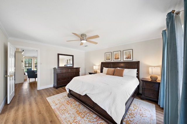 bedroom with a ceiling fan, baseboards, light wood finished floors, visible vents, and crown molding