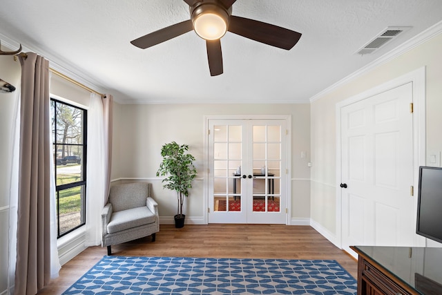 living area with visible vents, wood finished floors, french doors, crown molding, and baseboards