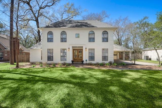 view of front facade with fence, driveway, a front lawn, french doors, and brick siding