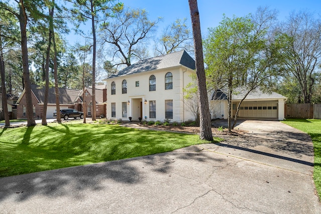 colonial home featuring a front yard, concrete driveway, fence, and roof with shingles