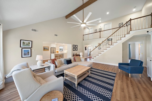 living room with stairs, beamed ceiling, wood finished floors, and visible vents