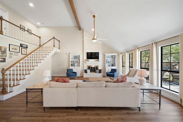 living room with beam ceiling, high vaulted ceiling, wood finished floors, and a fireplace