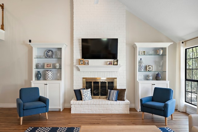 living area with a fireplace, wood finished floors, and vaulted ceiling