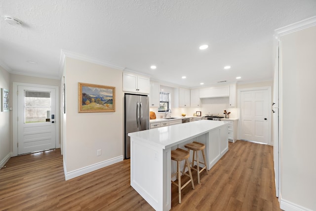 kitchen featuring a sink, appliances with stainless steel finishes, white cabinets, and light wood finished floors