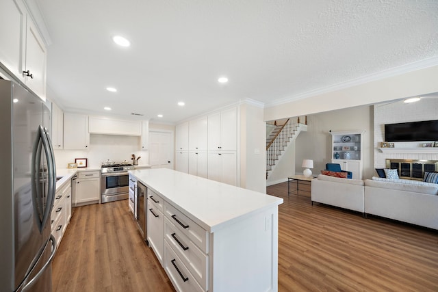 kitchen featuring open floor plan, white cabinets, appliances with stainless steel finishes, and wood finished floors