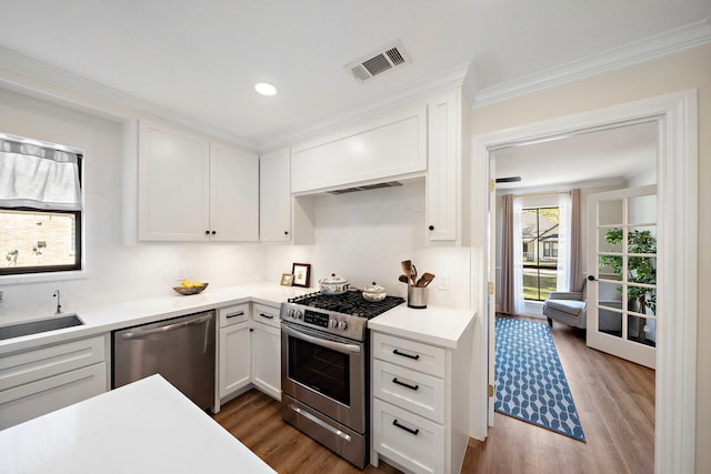 kitchen with wood finished floors, visible vents, a sink, stainless steel appliances, and white cabinets