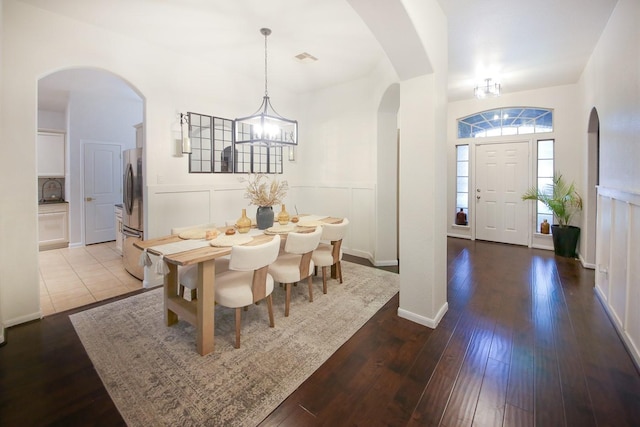 126 Magnolia Grove Ln, Conroe, TX 77384 - dining area featuring visible vents, a wainscoted wall, wood-type flooring, arched walkways, and an inviting chandelier