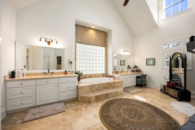 bathroom with high vaulted ceiling, a bath, a wealth of natural light, and a sink