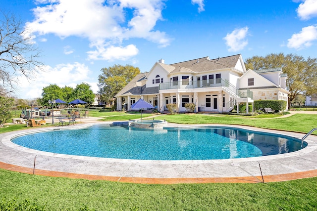 rear view of house featuring a patio, stairway, a pool with connected hot tub, a chimney, and a lawn