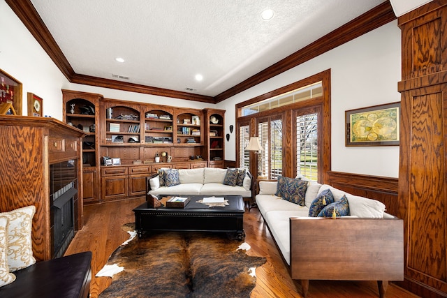 living room with dark wood-style flooring, a fireplace, and ornamental molding