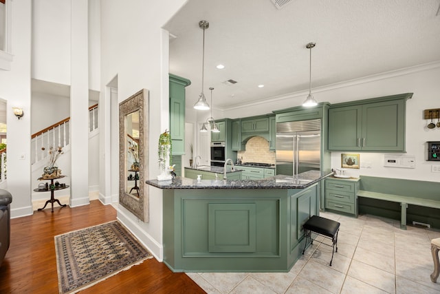 kitchen with dark stone countertops, pendant lighting, appliances with stainless steel finishes, and green cabinetry