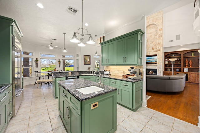 kitchen with a sink, a peninsula, green cabinets, and light tile patterned floors