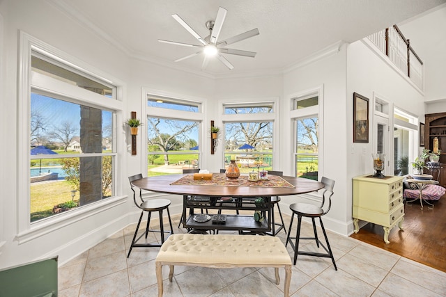 dining space featuring light tile patterned flooring, ceiling fan, crown molding, and baseboards