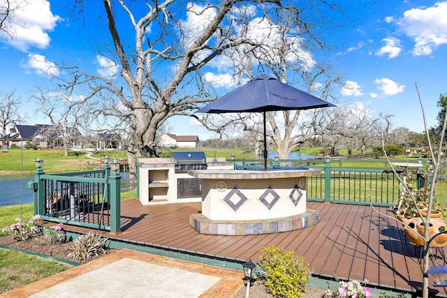 wooden terrace with exterior kitchen, a yard, and a grill