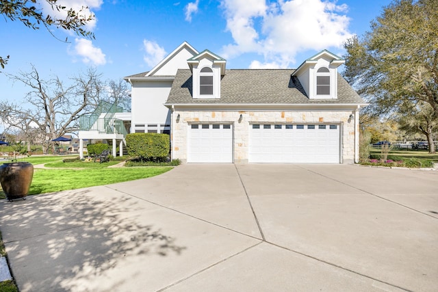 view of front facade with stone siding, a garage, a shingled roof, and a front lawn