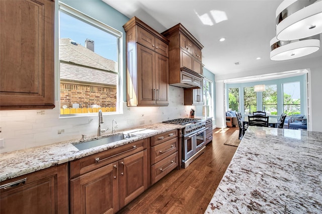 kitchen with a sink, double oven range, decorative backsplash, light stone countertops, and dark wood-style flooring