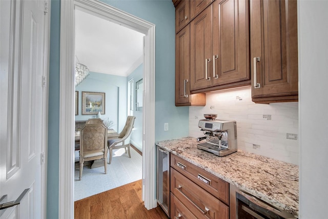 kitchen with beverage cooler, backsplash, light stone counters, and wood finished floors