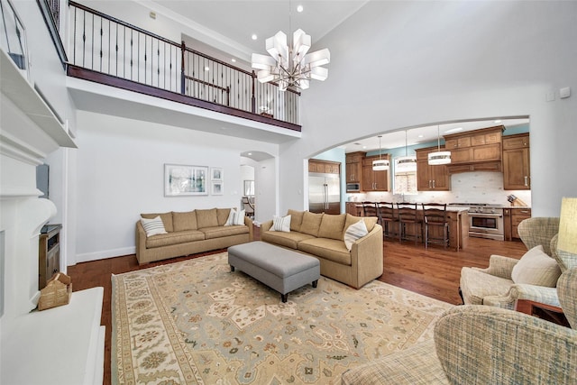 living room featuring baseboards, dark wood finished floors, an inviting chandelier, recessed lighting, and arched walkways