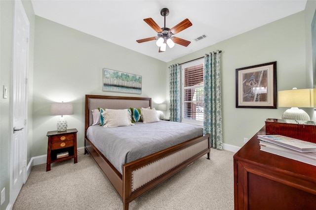 bedroom with visible vents, light colored carpet, baseboards, and ceiling fan