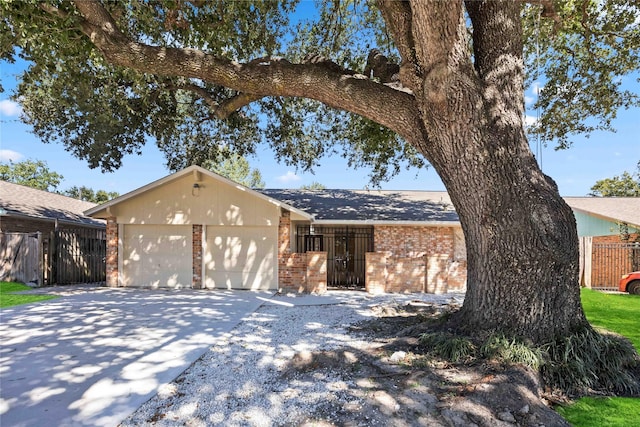 view of front of home featuring brick siding, an attached garage, concrete driveway, and fence