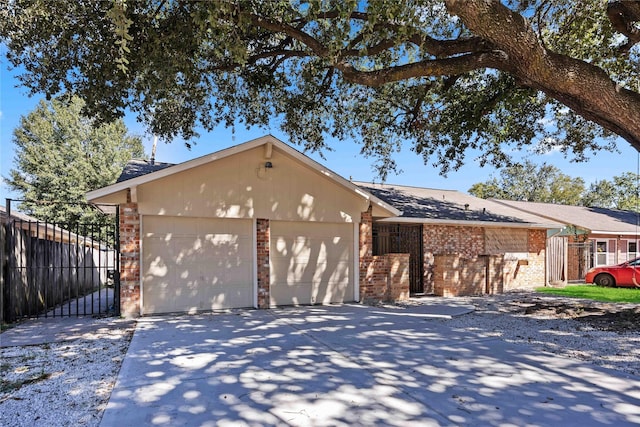 view of front of property featuring driveway, brick siding, an attached garage, and fence