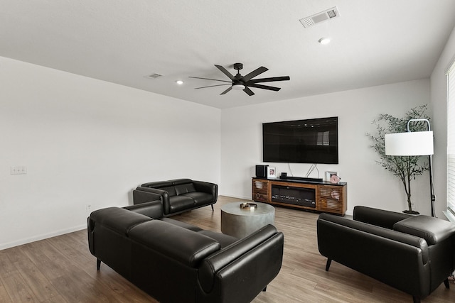 living room with visible vents, a ceiling fan, and wood finished floors