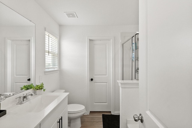 full bath featuring visible vents, toilet, wood finished floors, an enclosed shower, and vanity