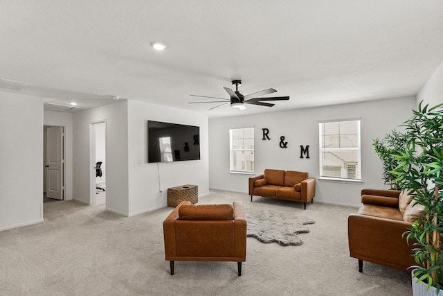 living area with baseboards, light colored carpet, and ceiling fan