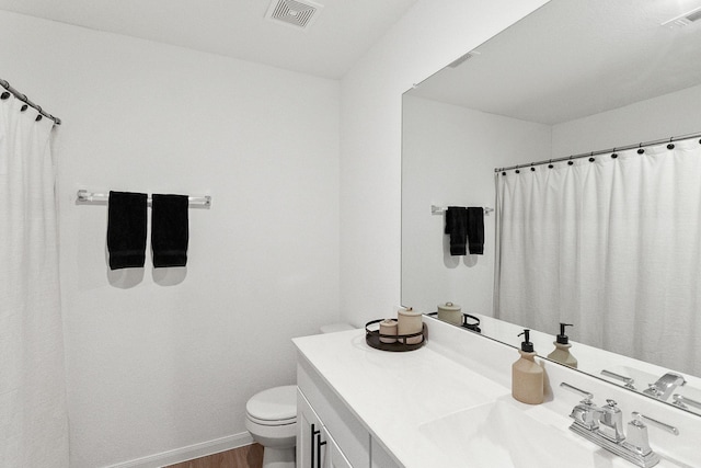 bathroom with visible vents, toilet, wood finished floors, and vanity