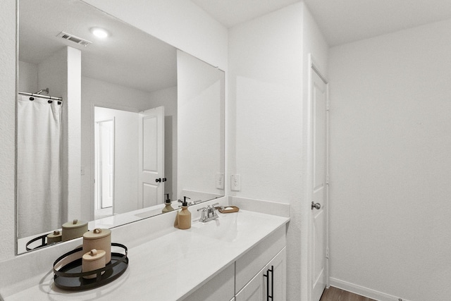 full bathroom featuring vanity, wood finished floors, baseboards, and visible vents