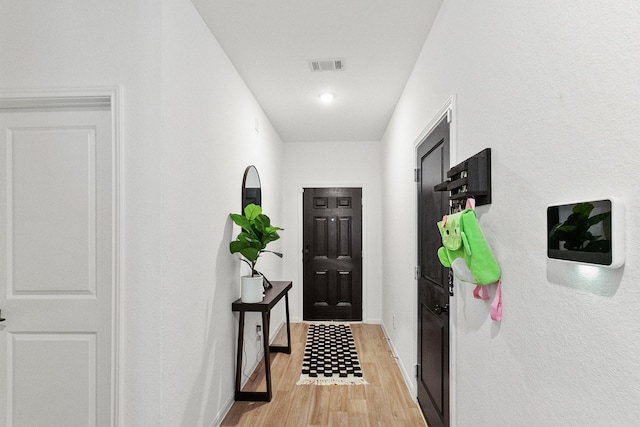 hall featuring visible vents, baseboards, and light wood-style floors