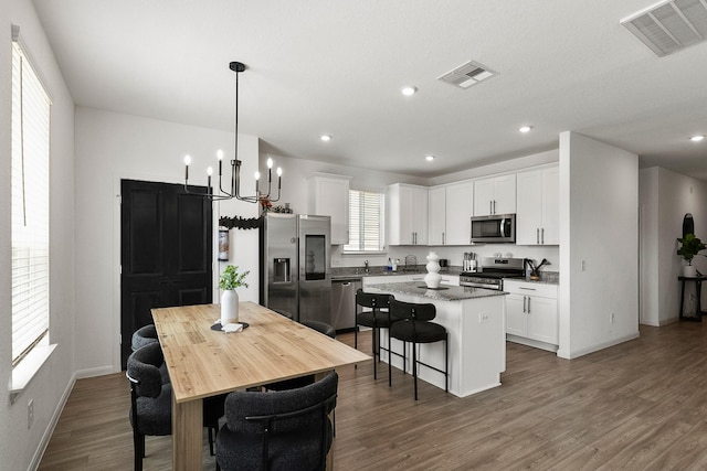 kitchen with a center island, visible vents, white cabinetry, and stainless steel appliances