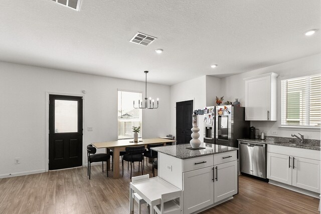 23515 Wrexham St, Spring, TX 77373 - kitchen featuring appliances with stainless steel finishes, a chandelier, a center island, wood finished floors, and white cabinets