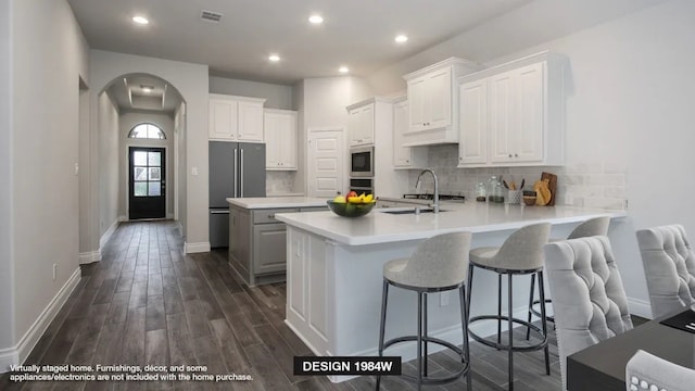 kitchen with visible vents, a peninsula, arched walkways, a sink, and appliances with stainless steel finishes