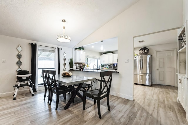 dining area featuring visible vents, baseboards, high vaulted ceiling, light wood-type flooring, and a textured ceiling