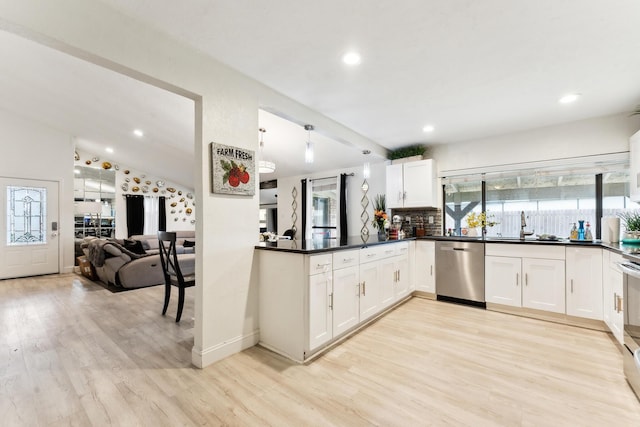 kitchen featuring dark countertops, decorative backsplash, appliances with stainless steel finishes, and light wood-style floors