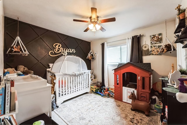 bedroom with a nursery area and a ceiling fan