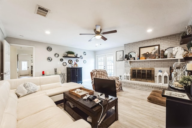 living room featuring visible vents, plenty of natural light, a fireplace, and wood finished floors