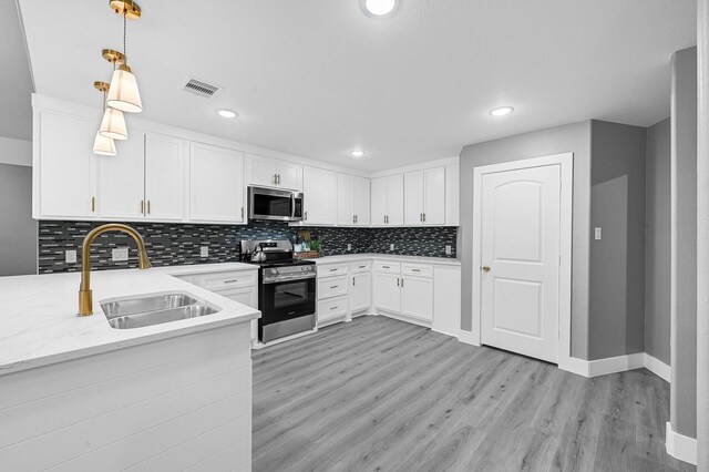 17127 Port O Call St, Crosby, TX 77532 - kitchen featuring a sink, backsplash, white cabinetry, appliances with stainless steel finishes, and light wood finished floors