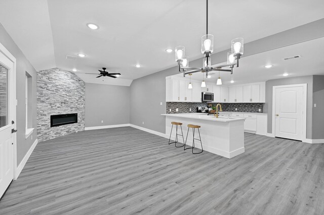17127 Port O Call St, Crosby, TX 77532 - kitchen with visible vents, a stone fireplace, vaulted ceiling, stainless steel microwave, and backsplash