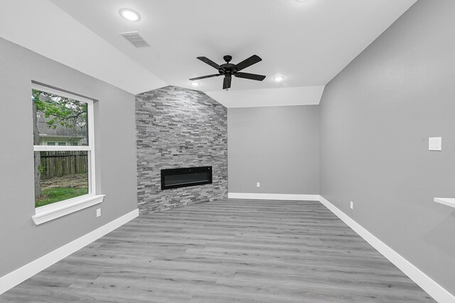 17127 Port O Call St, Crosby, TX 77532 - unfurnished living room featuring visible vents, baseboards, lofted ceiling, a stone fireplace, and wood finished floors