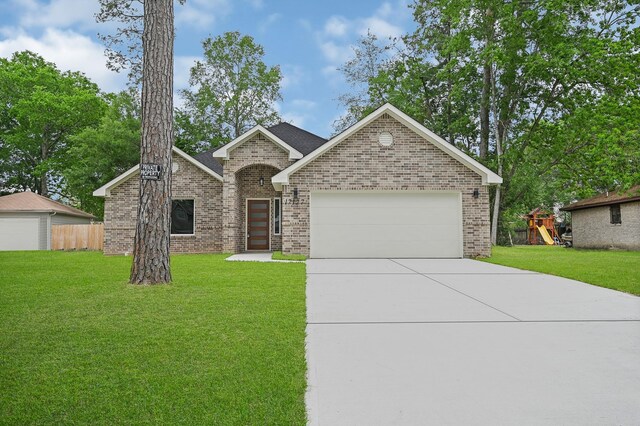 17127 Port O Call St, Crosby, TX 77532 - view of front of property featuring brick siding, a playground, a front lawn, concrete driveway, and a garage