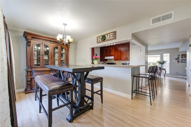 dining space featuring a notable chandelier, light wood-style floors, visible vents, and baseboards